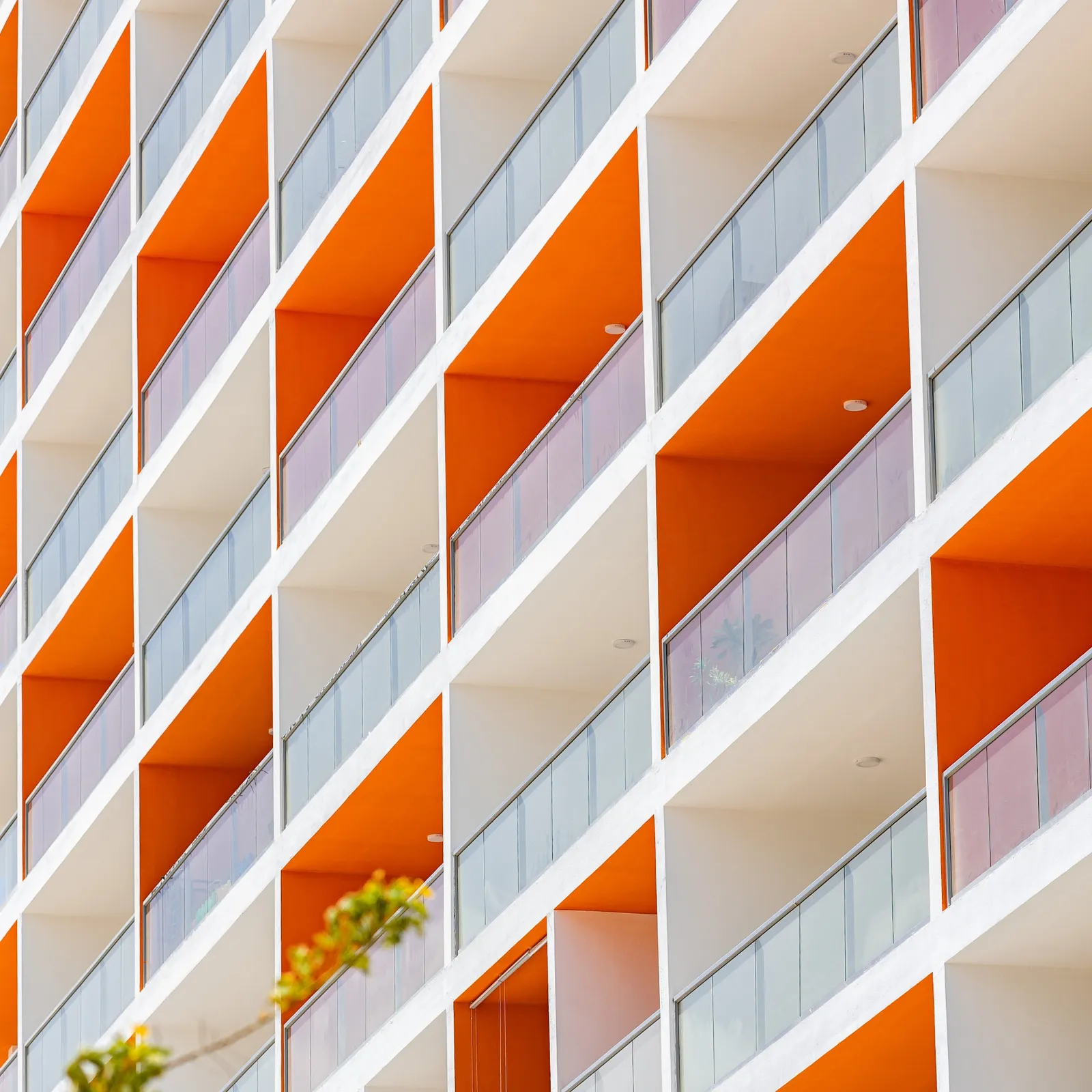 Edifício residencial com varandas em destaque e composição geométrica em tons claros e laranja.